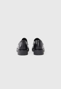 Black leather shoes with a smooth texture, rounded shape, and thick rubber sole. Features a subtle stitch detail and minimal hardware accents.