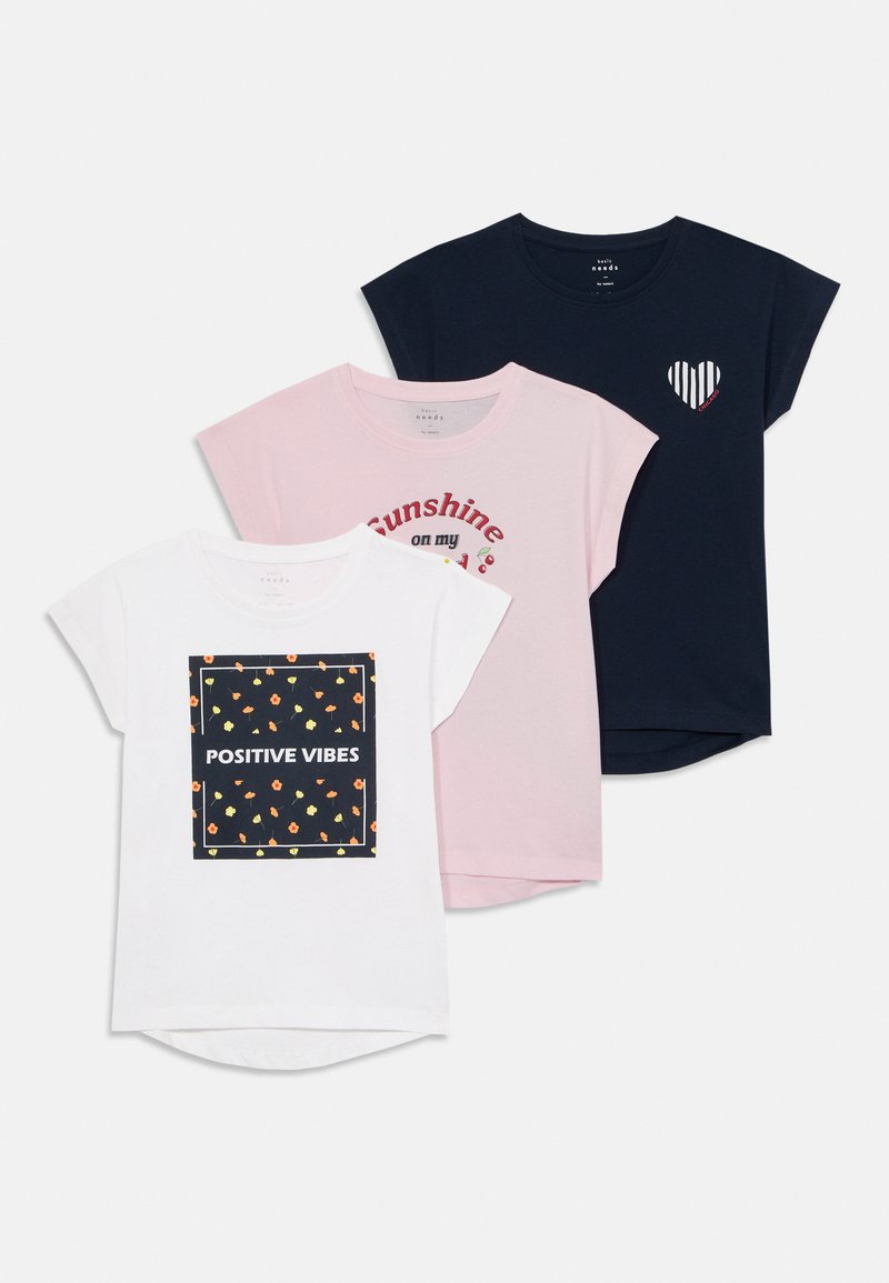 Tres camisetas: blanca con un patrón floral y "VIBRACIONES POSITIVAS", rosa con "Sol radiante" y azul marino con un acento de corazón a rayas. Material de algodón.