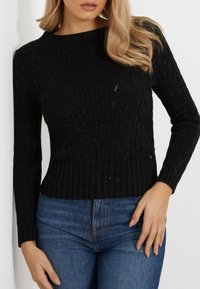 Musta ribbed neulepaita, jossa on teksturoitu kaapelitekstuuri, pitkät hihat ja tiukka malli. Sopii arkikäyttöön.