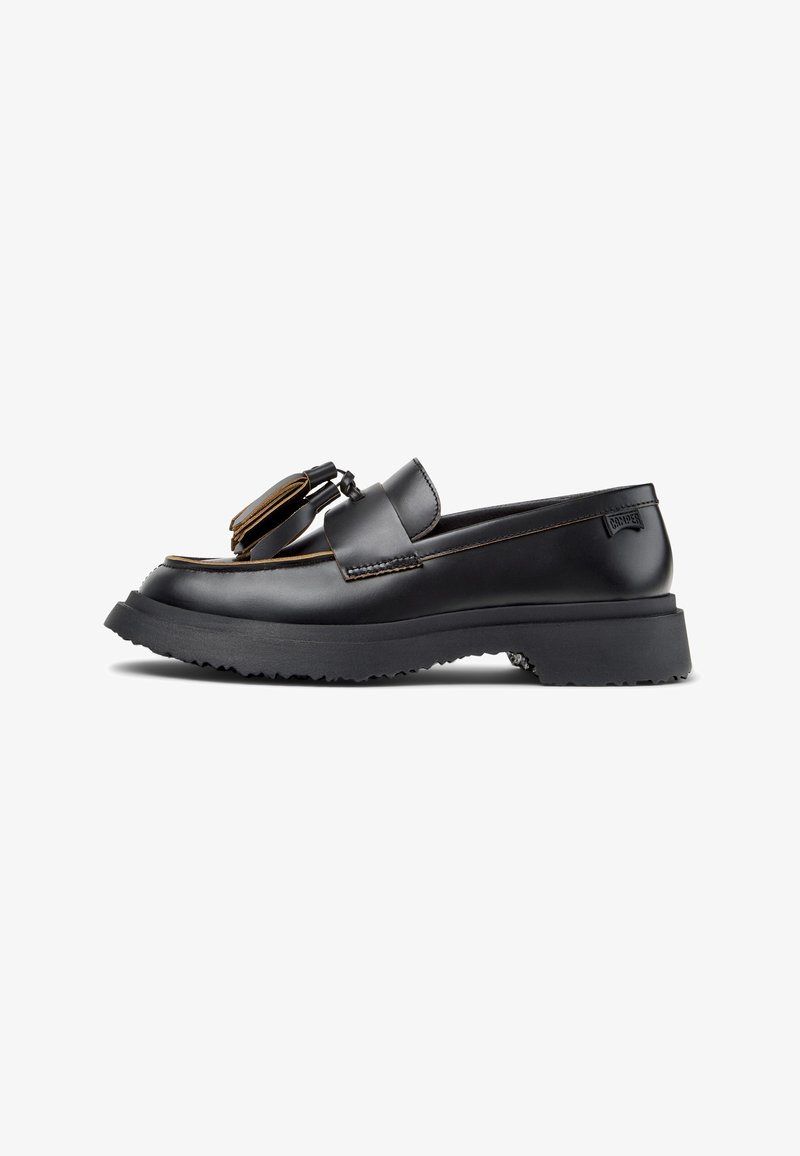 Schwarzer Lederloafer mit abgerundetem Zehenbereich, dicker Gummisohle, dekorativem Riemen und Ziernähten. Glatte Textur mit mattem Finish.
