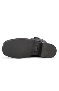 Semelle de botte noire avec une surface en caoutchouc texturé, présentant un design courbé et une zone de talon renforcée pour la durabilité. Taille indiquée comme 37.