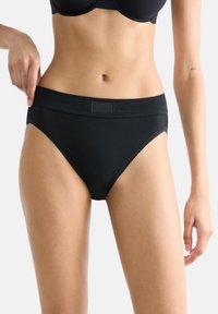 Schwarze Baumwollunterhose mit breitem Bund und glatter Textur. Sie verfügt über ein dezentes Logo am Bund und hat ein klassisch hochgeschnittenes Design.