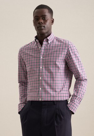 Chemise à carreaux en rose, bleu et blanc. Avec un col, des manches longues et une coupe ajustée. Associée à un pantalon noir.