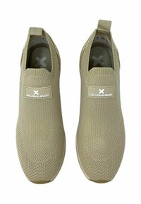 Zapatos de lona beige tipo slip-on con una parte superior de malla texturizada, punta redondeada y un parche con el logo en el lateral. Diseñados sin cordones para facilitar su uso.
