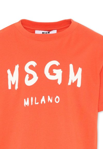 T-shirt orange à manches courtes avec logo MSGM blanc en gras et texte "MILANO" imprimé sur le devant, sous un col rond.