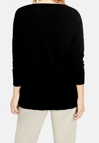 Pull en maille noir à coupe décontractée, manches longues et encolure arrondie, avec une texture lisse et un minimalisme dans les détails.