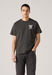 Gray cotton t-shirt with short sleeves, featuring a white graphic that says "GOOD LUCK" with a lion design on the left chest area.