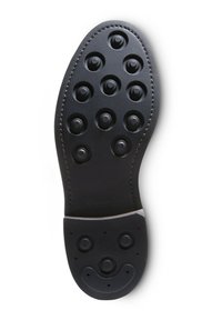 Zool van een zwarte leren nette schoen met verhoogde ronde studs en gestikte randen, gezien vanaf de onderkant.