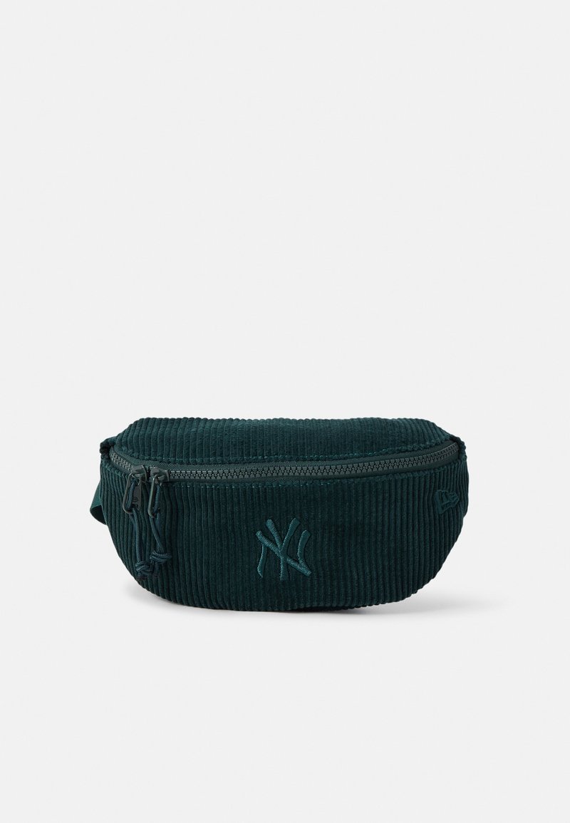 Mørkegrøn bæltetaske i fløjl med lynlås og broderet logo foran, vist på en ensfarvet hvid baggrund.