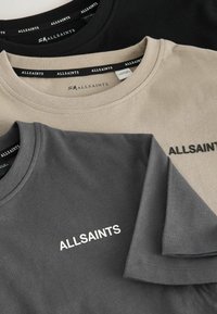 Trys marškiniai: juodi, kreminiai ir anglies pilki, sulankstyti kartu. Kiekvienas turi apvalų kaklą ir baltomis raidėmis užrašytą "ALLSAINTS" priekyje.