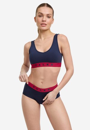 Marineblauwe sportbeha en bijpassende slip met een rode elastische band. De band heeft het "FALKE"-logo. Soepele textuur, rekbaar materiaal.
