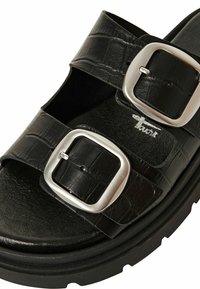 Svarta sandaler med två justerbara silverfärgade spännen, tillverkade av texturerat syntetiskt läder. Har en tjock plattformssula för extra höjd.