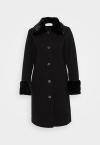 Manteau noir avec un col et des poignets en fausse fourrure, fermeture à six boutons et poches latérales. Fabriqué à partir d'un tissu texturé, au design épuré.