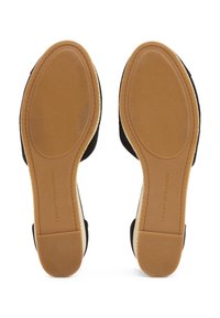 Paire de chaussures beige à semelle en caoutchouc avec une adhérence texturée et le marquage "Tommy Hilfiger" visible sur les semelles orientées vers le haut.
