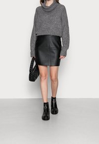Maglione grigio con collo a cappuccio, mini gonna nera in pelle e stivali neri alla caviglia con cerniera frontale. Abbinato a una borsa nera intrecciata.