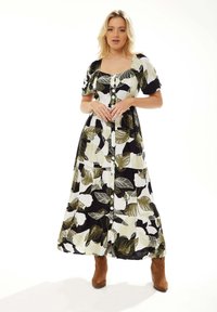 Maxi dress in black and white with green leaf patterns, featuring short puffed sleeves, a square neckline, and front buttons.