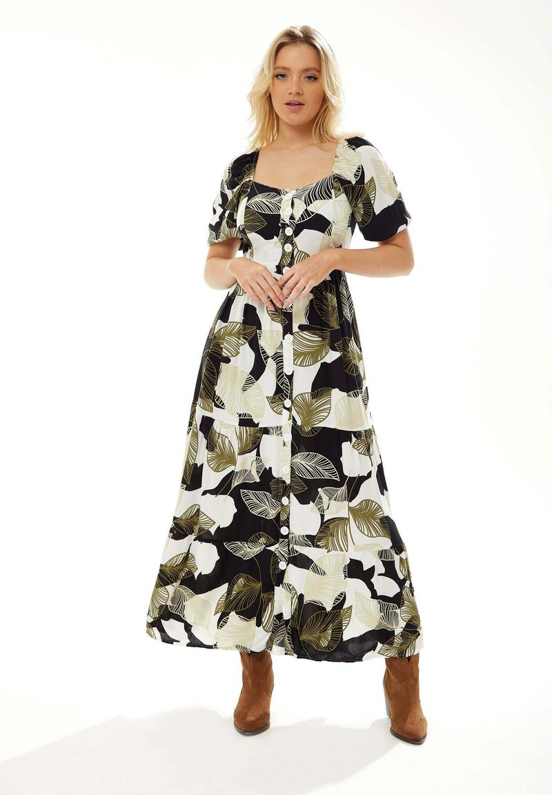 Maxi dress in black and white with green leaf patterns, featuring short puffed sleeves, a square neckline, and front buttons.