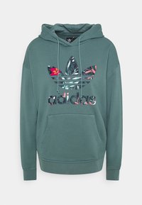 Grön bomullshuvtröja med en stor flerfärgad blommig Adidas-logotyp och ficka, med justerbar snoddhuva och ribbade ärmslut.