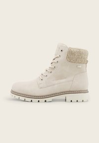 Bottine beige à lacets avec col en tricot texturé, semelle robuste et œillets métalliques, conçue pour un usage décontracté et en extérieur.