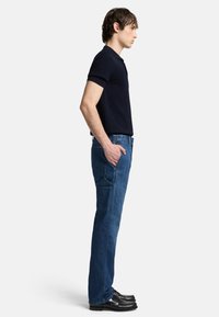 Polo shirt blu navy, pantaloni in denim blu, vestibilità slim, gamba dritta, cinque tasche, indossati con scarpe nere, design minimalista, texture semplice.