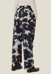 Blomsterpræget brede bukser med et sort og blåt design på en lys baggrund. Fremstillet af et blødt, let stof med lommer.