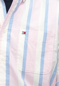 Πουκάμισο με κοντά μανίκια και κουμπιά, σε ροζ, άσπρες και μπλε ρίγες, με μπροστινή τσέπη που φέρει μικρό λογότυπο. Κατασκευασμένο από βαμβακερό ύφασμα.