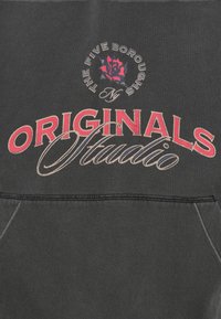 Σκούρο γκρι φούτερ με κόκκινο και μπεζ κείμενο που γράφει "ORIGINALS Studio" και ένα μικρό γραφικό τριαντάφυλλο από πάνω με το κείμενο "The Five Boroughs NY."