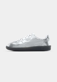 Baskets argentées avec une tige lisse et réfléchissante, dotées de semelles en caoutchouc noires et d'un design classique à lacets. Logo Puma sur le côté.