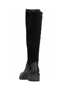 Botas negras hasta la rodilla con parte superior de ante, puntera redonda y un tacón bajo cuadrado. Cuentan con una correa decorativa y una hebilla en el lado.