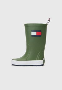 Botte de pluie en caoutchouc verte avec une semelle blanche. Présente un patch logo rouge, blanc et bleu sur le côté. Texture lisse, hauteur mi-mollet.