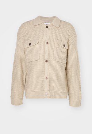 Cardigan bej tricotat cu închidere prin butoane, două buzunare la piept și tiv și manșete cu dungă. Modelul texturat adaugă adâncime țesăturii.