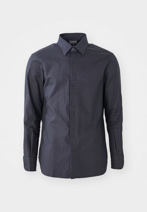 Chemise noire à manches longues avec col, présentant un motif texturé et des poignets boutonnés. Fabriquée en tissu lisse dans une couleur unie.