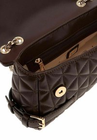 Sac à main matelassé marron avec une finition en cuir lisse, des accessoires dorés et un intérieur zippé. Comprend une fermeture à bouton-pression et une bandoulière réglable.