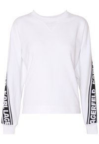 Bílá mikina s dlouhými rukávy, žebrovaným výstřihem a černým brandingem na stranách. Má volný střih a měkkou texturu látky.