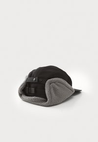 Svart caps med grå fleeceøreflapper. Har en buet skygge, justerbar stropp og trykknapplukking bak. Stoffet er mykt og varmt.