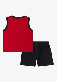 Sarkans sporta t-krekls ar melnu apdari, kombinēts ar melnām šortām ar elastīgu jostasvietu. Izgatavots no elpojoša auduma, ideāli piemērots aktīvai atpūtai.