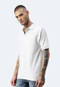 Hellgraues Poloshirt aus Baumwolle. Mit klassischem Kragen, kurzen Ärmeln und einer Knopfleiste mit einem einzigen Knopf. Glatte Textur, taillierte Passform.