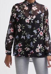 Chemise noire transparente à boutons avec un motif floral en rose, bleu et vert. Manches longues et col classique.