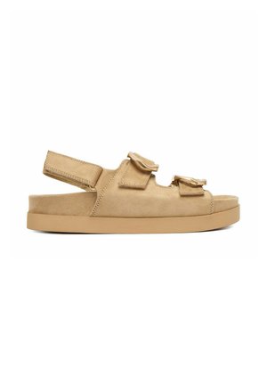 Beige suede sandal with two adjustable Velcro straps over the foot and one around the heel on a flat rubber sole.