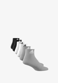 Calcetines tobilleros en negro, blanco y gris dispuestos en un degradado; mezcla de algodón con puños acanalados y logo de Adidas en cada calcetín.