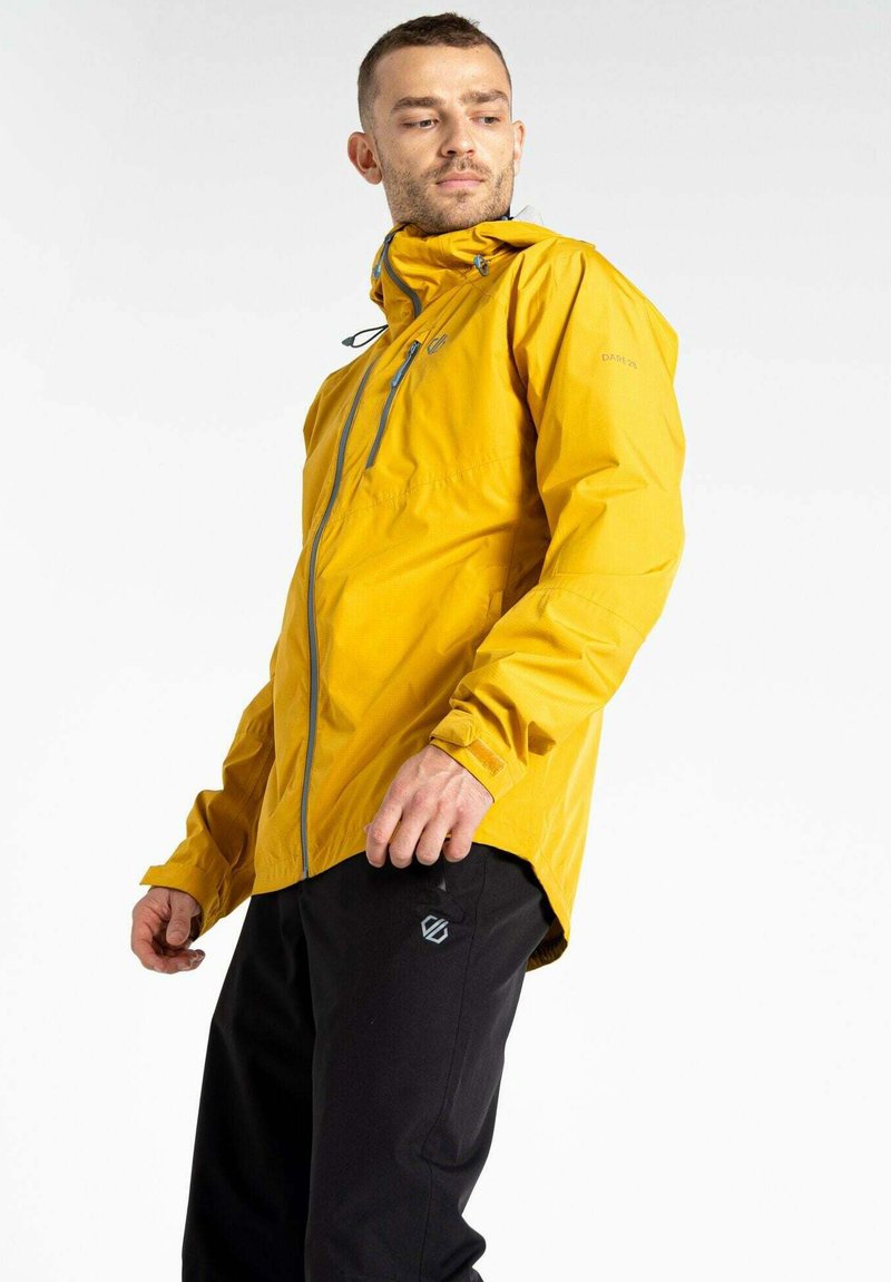 Gelbe wasserdichte Jacke mit Kapuze, Frontreißverschluss, verstellbaren Manschetten und grauen Akzenten; kombiniert mit schwarzen Hosen mit einem Logo.