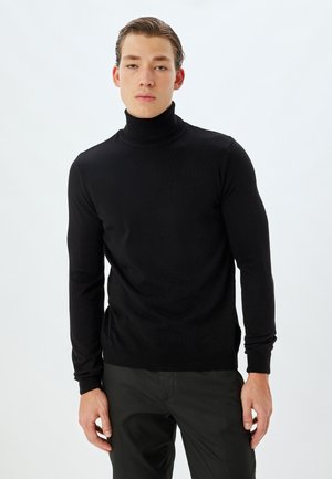 Suéter negro de cuello alto hecho de un suave tejido de punto liviano. Diseño ajustado con mangas largas y puños acanalados.