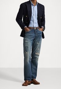 Marinblå blazer, ljusblå skjorta, slitna blå jeans med lappar, brunt läderbälte och bruna dressade skor. Avslappnad men ändå polerad look.