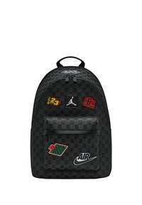 Zaino nero con tessuto strutturato, caratterizzato da varie toppe colorate, tra cui il logo Jumpman e la scritta "AIR" in bianco.