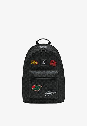 Zaino nero con tessuto strutturato, caratterizzato da varie toppe colorate, tra cui il logo Jumpman e la scritta "AIR" in bianco.