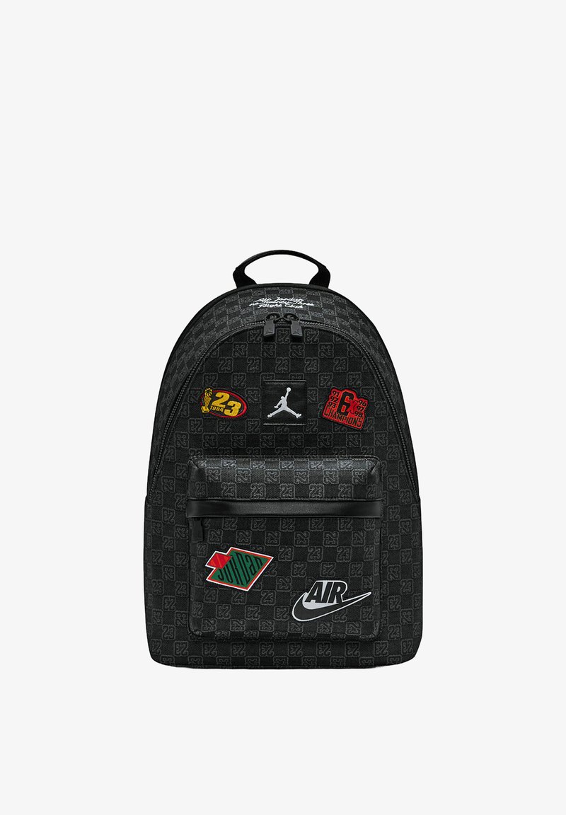 Zaino nero con tessuto strutturato, caratterizzato da varie toppe colorate, tra cui il logo Jumpman e la scritta "AIR" in bianco.