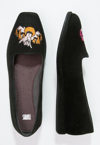 Ballerine in suede nero con punta quadrata, caratterizzate da vivaci ricami raffiguranti mani e sole. Interno morbido e testurizzato con suola flessibile.