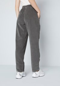 Grijze corduroy broek met elastische tailleband, zijzakken en een ontspannen pasvorm. Gecombineerd met witte en zilveren sneakers.