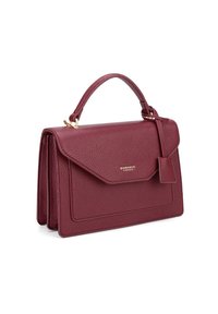 Bordeaux leren handtas met een gestructureerde vorm, bovenhandvat, magnetische klep sluiting en een klein baggage tag. Textuur met gouden accenten.