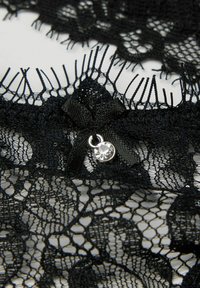 Zwarte kanten rand met een bloemenpatroon, voorzien van een lint strik en een kleine strass accent. Ingenieuze textuur en open geweven ontwerp.